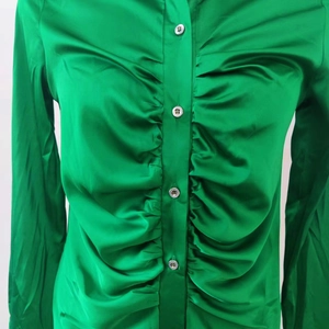 Dettaglio camicia in raso verde smeraldo con eleganti increspature e bottoni perlati