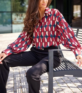 Détail d'un chemisier soyeux à manches longues imprimé géométrique et pantalon noir chic