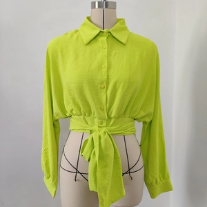 Detail of neon green tie-waist shirt featuring long sleeves and textured crinkle fabric