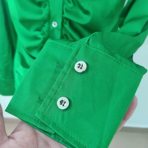 Dettaglio del polsino della camicia verde brillante con eleganti bottoni di perla bianca