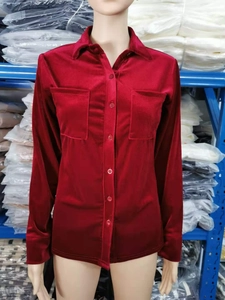 Detail of burgundy velvet shirt featuring double chest pockets and glossy fabric texture