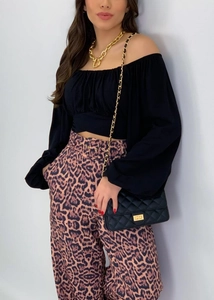 Détail des manches bouffantes et de l'encolure bateau sur une blouse noire courte