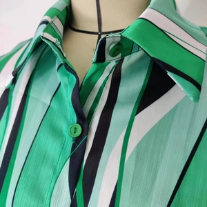 Dettaglio del colletto della camicia a righe verdi e bianche con tessuto lucido e bottoni