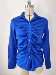 Dettaglio elegante camicia in raso blu brillante con davanti arricciato e bottoni argentati