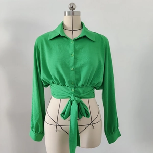 Detail of light green tie-waist shirt featuring front buttons and a large bow belt