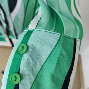 Dettaglio della manica di camicia a righe verdi con cuciture e bottoni verdi