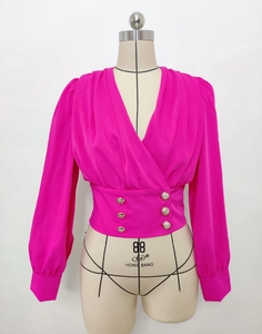 Detail of V-neck rose pink shirt featuring puff sleeves and gold decorative waist buttons