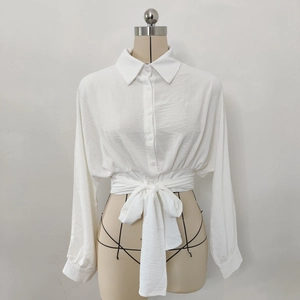Detail of white cropped shirt showing the bow-tie waist and textured fabric stitching
