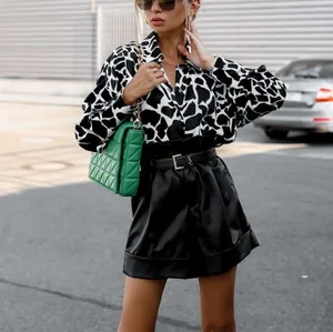 Détail d'un chemisier à motif vache avec short en cuir et sac matelassé vert élégant