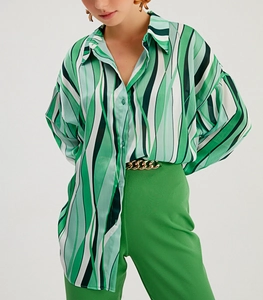 Dettaglio camicia a maniche lunghe con stampa geometrica verde e cintura dorata