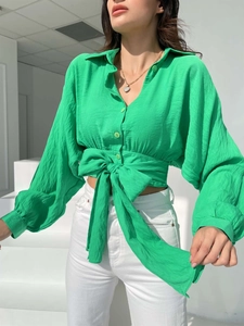 Detail of green textured long sleeve shirt featuring a front tie bow and button-up V-neck
