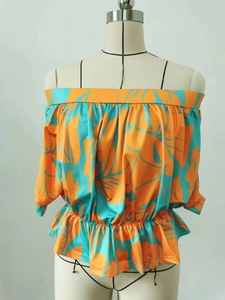 Detail of off-shoulder tropical print top with smocked waist and turquoise leaf pattern