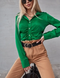 Dettaglio della camicia in raso verde brillante con pieghe anteriori e bottoni di perle