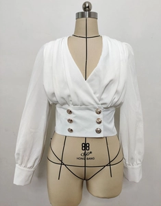 Detail of white V-neck wrap blouse with pleated shoulders and gold double-breasted buttons