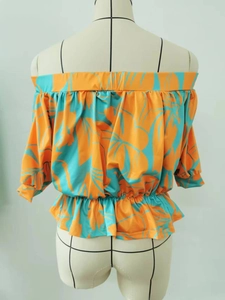 Detail of tropical palm leaf print and elastic waist on orange off-shoulder blouse