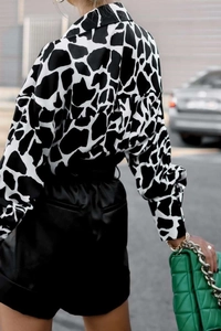Détail d'un chemisier ample à manches longues pour femmes avec imprimé girafe noir et blanc