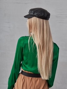 Dettaglio di un cappello newsboy nero in ecopelle abbinato a una camicia di seta verde