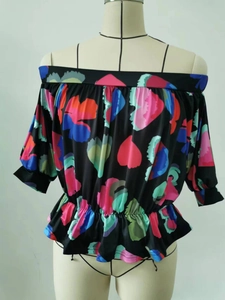 Detail of off-shoulder black blouse with colorful floral prints and elastic smocked waist