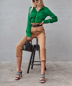 Dettaglio della camicia di raso verde lucido con pieghe eleganti e cintura con fibbia nera