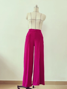 Detail view of high waist rose red wide leg trousers showing front seam and button closure