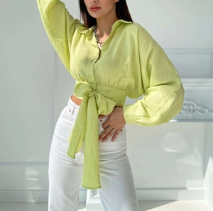 Detail of light green short blouse with balloon sleeves and waist tie design