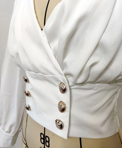 Detail of white V-neck shirt featuring luxury golden lion embossed double-breasted buttons