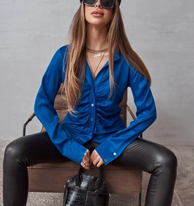 Dettaglio camicia in raso blu reale con texture plissettata e chiusura a bottoni