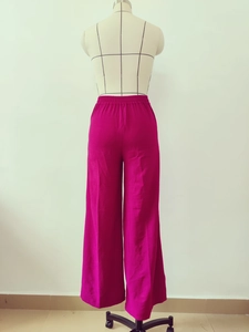 Detail of the elastic waistband and textured fabric on magenta wide-leg trousers