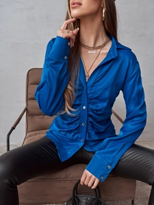 Dettaglio della camicia di raso blu reale con drappeggio frontale e trama in seta