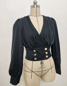 Detailed view of the V-neck black blouse featuring elegant gold buttons and puffy sleeves