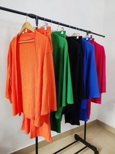 Dettaglio di set due pezzi plissettati colorati appesi a un appendiabiti in cinque colori vivaci