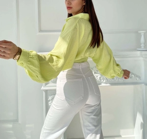 Detail showing the light yellowish-green lantern sleeves and micro-textured fabric of the shirt
