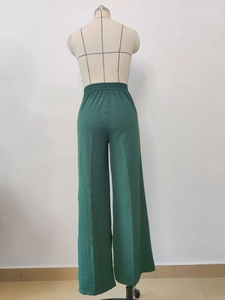 Detail view of dark green pleated wide-leg trousers with elastic high waist on mannequin
