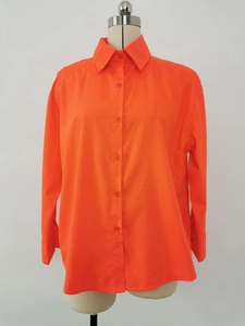 Detail of bright orange button-down shirt featuring a classic collar and smooth fabric