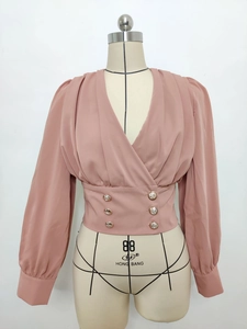 Detail of V-neck wrap blouse with decorative gold buttons and wide waistband design