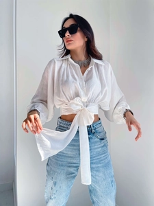 Close-up of white short-cut blouse with elegant waist tie and lantern sleeve details