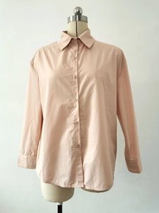 Detail of apricot long sleeve shirt showing lapel collar and single-breasted button design