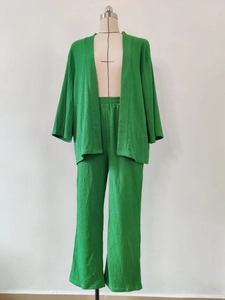Dettaglio del set due pezzi verde in tessuto stropicciato con pantaloni a gamba larga