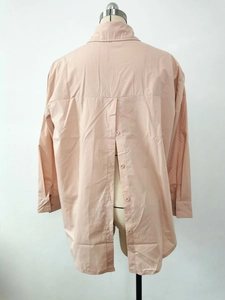 Detail of pink long-sleeve shirt featuring unique button-back design and split hem
