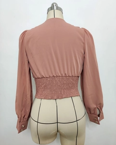Detail view of pink long sleeve shirt with bubble sleeves and gold buttons on cuffs