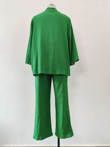 Dettaglio della trama in tessuto plissettato verde sul set tunica a maniche lunghe e pantaloni