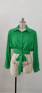Detail of green cropped shirt with front tie knot and textured long sleeves