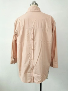 Detail view of the back button design on this loose apricot long-sleeved shirt