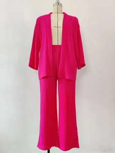 Dettaglio di un completo fucsia a due pezzi con texture a pieghe, top e pantaloni ampi