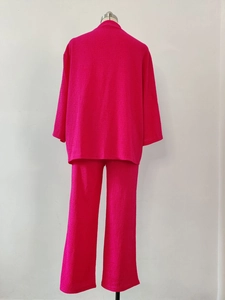 Dettaglio del completo a due pezzi rosa in tessuto stropicciato con pantaloni casual
