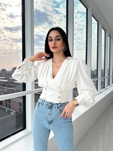 Detail of white V-neck shirt showing puffy sleeves and golden decorative buttons