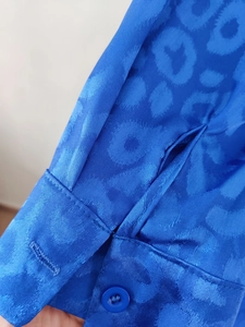 Detail shot of blue jacquard leopard print sleeve cuff with a satin finish and button