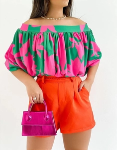 Detail of vibrant floral off-shoulder top paired with orange high-waisted shorts