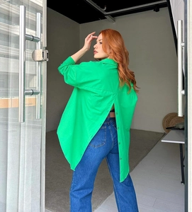 Detail of the oversized green shirt featuring a unique button-up split back design