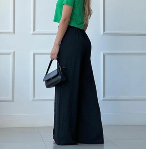 Detail view of black high-waisted wide-leg trousers with elegant drape and relaxed fit